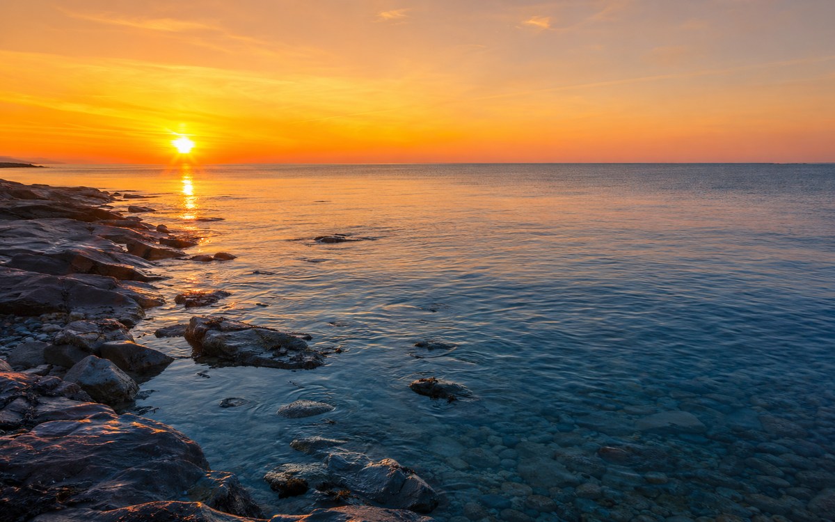 Морская вода у каменистого берега на закате